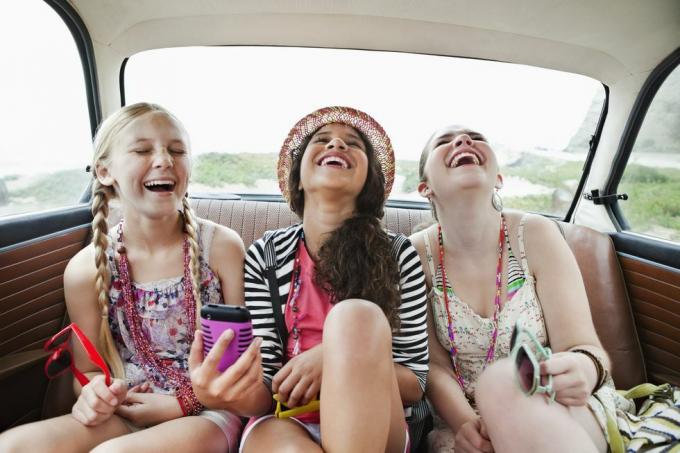 τρία κορίτσια που γελούν στο πίσω κάθισμα ενός οχήματος