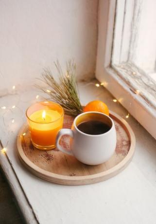 άνετες χειμερινές λεπτομέρειες εσωτερικού σπιτιού, φλιτζάνι καφέ, ξύλινος δίσκος, μανταρίνι και κεριά νεκρή φύση για τα Χριστούγεννα