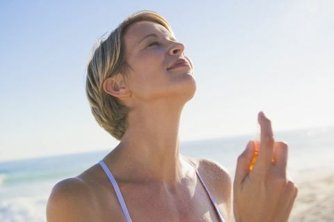 Γυναίκα ψεκάζοντας άρωμα στο λαιμό της στην παραλία