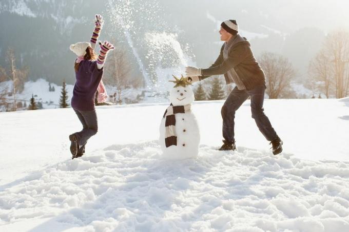 ζευγάρι κάνει χιονάνθρωπο και παίζει στο χιόνι