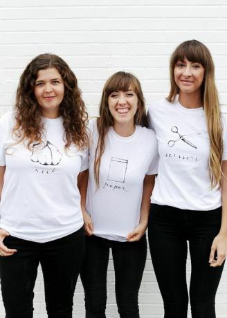 τρεις γυναίκες με λευκά μπλουζάκια, με ροκ, χαρτί ή ψαλίδι γραμμένες και απεικονισμένες στο πουκάμισο