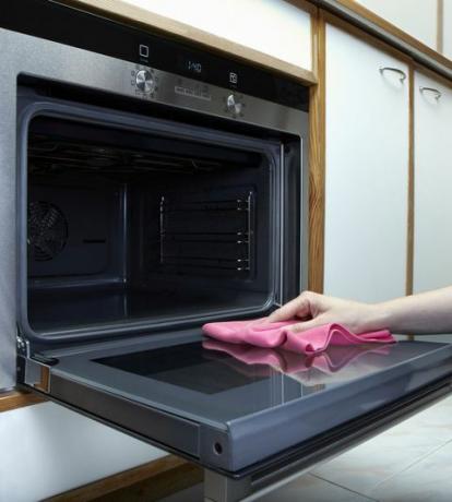 Οι γυναίκες καθαρίζουν το φούρνο με πετσέτα