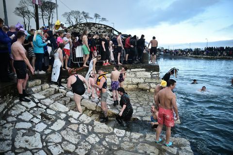 Carnlough, Βόρεια Ιρλανδία 01 Ιανουαρίου ένα μεγάλο πλήθος θεατών παρακολουθεί τους κολυμβητές καθώς παίρνουν μέρος στο ετήσιο νέο χρόνια μέρα κολύμπι στο λιμάνι Carnlough την 1η Ιανουαρίου 2018 στο Carnlough της Βόρειας Ιρλανδίας φωτογραφία από τον charles mcquillangetty εικόνες