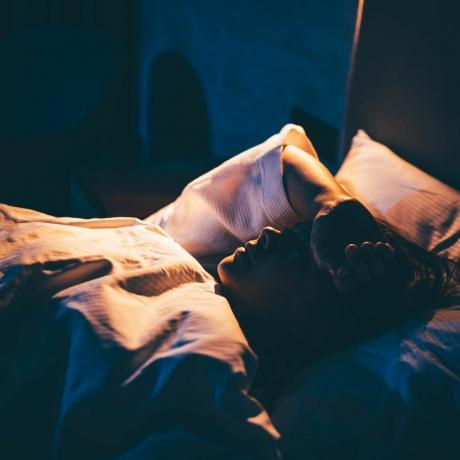 γυναίκα με αϋπνία νεαρή γυναίκα ξαπλωμένη στο κρεβάτι με το χέρι στο μέτωπο