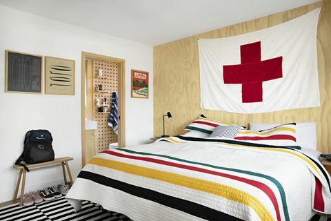 υπνοδωμάτιο raili clasen με ριγέ πάπλωμα και μεγάλη σημαία του Ερυθρού Σταυρού