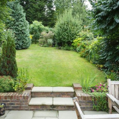 με βεράντα και διαμορφωμένο πίσω κήπο στην Αγγλία, το Ηνωμένο Βασίλειο με αίθριο, γρασίδι και πέτρινα σκαλοπάτια