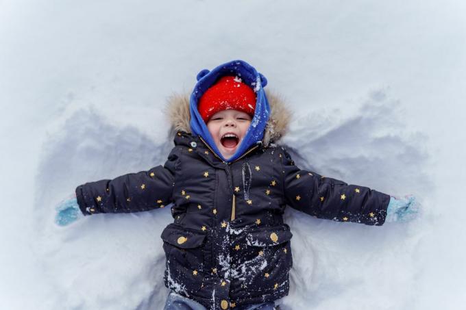μικρό παιδί στο χιόνι κάνοντας χιόνι άγγελος