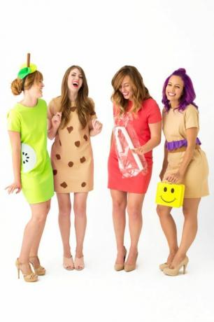 τέσσερις γελώντας γυναίκες με κοντό φορέματα ντυμένες ως «κυρίες μεσημεριανού γεύματος», μια με κουτί με κίτρινο χαμόγελο προσώπου